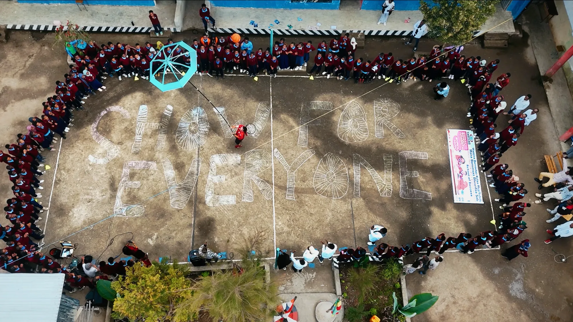 Show For Everyone written in chalk in a schoolyard surrounded by children
